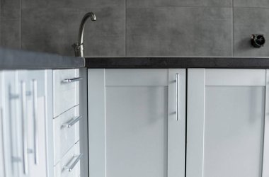 Modern minimalizm stili mutfak iç dekorasyonu tek renkli tonlarda. Mutfak kaputu ve lavabosu olan gri beyaz bir mutfak ve koyu gri bir tezgah. Chipboard 'dan modüler mutfak.