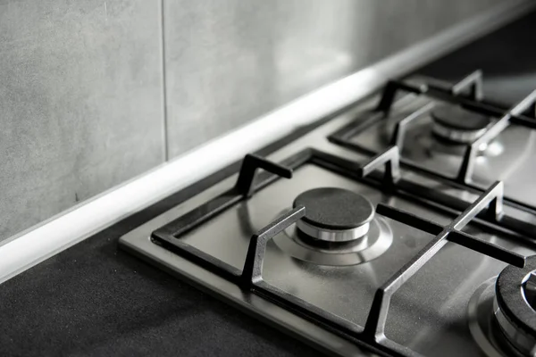Metalowy piec gazowy ze stali nierdzewnej montowany na kuchni z ciemnoszarym blatem. — Zdjęcie stockowe