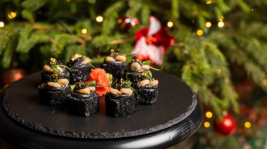 Siyah pirinçli suşi, yengeç eti, avokado, tütsülenmiş somon kreması, kürek havyarı, masago, karides kokteyli ve zencefilli altın yaprak..