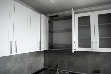 Modern minimalizm stili mutfak iç dekorasyonu tek renkli tonlarda. Mutfak kaputu ve lavabosu olan gri beyaz bir mutfak ve koyu gri bir tezgah. Chipboard 'dan modüler mutfak.