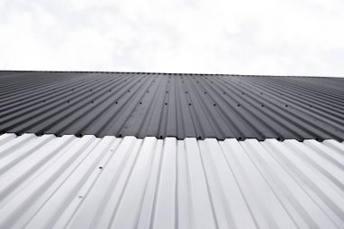 Bir depo veya fabrika cephesi olarak kullanılan siyah ve beyaz kıvrımlı demir çarşaf. Sivri uçlu çinko kaplamalı metal alüminyum cephenin dokusu. Mimarlık. Metal doku.