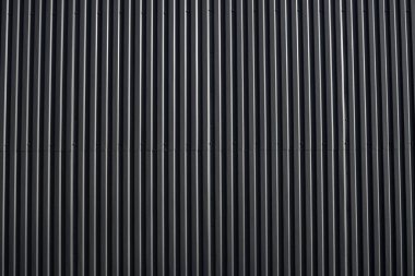 Bir depo ya da fabrika cephesi olarak kullanılan siyah kıvrımlı demir çarşaf. Sivri uçlu çinko kaplamalı metal alüminyum cephenin dokusu. Mimarlık. Metal doku.