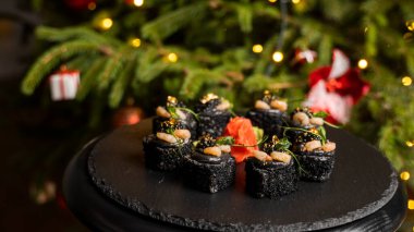 Siyah pirinçli suşi, yengeç eti, avokado, tütsülenmiş somon kreması, kürek havyarı, masago, karides kokteyli ve zencefilli altın yaprak..