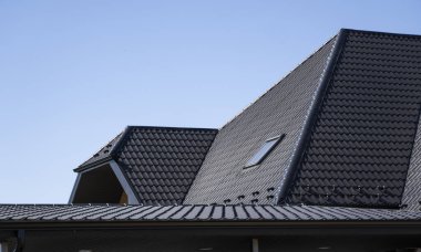 Çatı penceresi olan modern bir eve kahverengi çatılı metal profil çatısı. Çürük çarşafın çatısı. Metal profil dalgalı şeklinin çatısı. Metalden yapılmış modern çatı. Metal çatı..