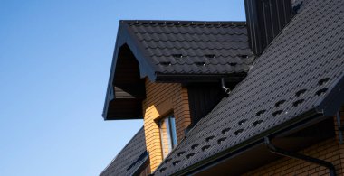 Çatı penceresi olan modern bir eve kahverengi çatılı metal profil çatısı. Çürük çarşafın çatısı. Metal profil dalgalı şeklinin çatısı. Metalden yapılmış modern çatı. Metal çatı..