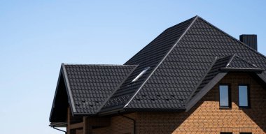 Çatı penceresi olan modern bir eve kahverengi çatılı metal profil çatısı. Çürük çarşafın çatısı. Metal profil dalgalı şeklinin çatısı. Metalden yapılmış modern çatı. Metal çatı..