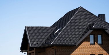 Brown corrugated metal profile roof installed on a modern house with a attic windows. The roof of corrugated sheet. Roofing of metal profile wavy shape. Modern roof made of metal. Metal roofing. clipart