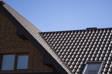 Modern bir eve kahverengi, metal profil çatısı döşenmiş. Çürük çarşafın çatısı. Metal profil dalgalı şeklinin çatısı. Metalden yapılmış modern çatı. Metal çatı..