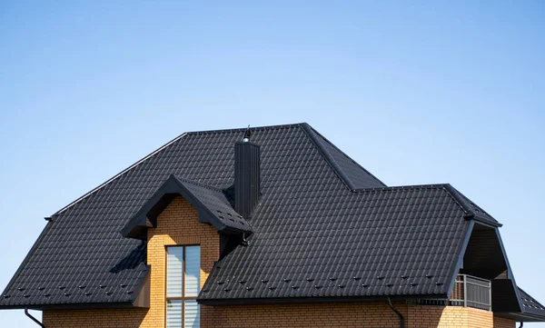 Braune Wellblechprofildächer auf einem modernen Haus mit Dachbodenfenstern. Das Dach aus Wellblech. Überdachung von Metallprofilwellenform. Modernes Dach aus Metall. Metalldächer. — Stockfoto