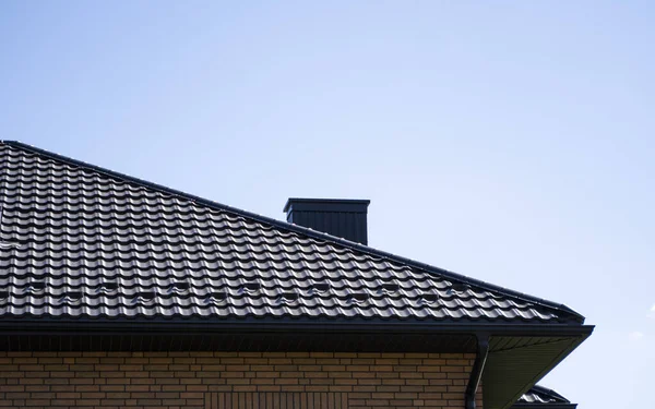 Brown corrugated metal profile roof installed on a modern house. The roof of corrugated sheet. Roofing of metal profile wavy shape. Modern roof made of metal. Metal roofing.