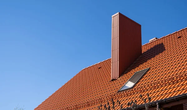 Red corrugated metal profile roof installed on a modern house. The roof of corrugated sheet. Roofing of metal profile wavy shape. Modern roof made of metal. Metal roofing.