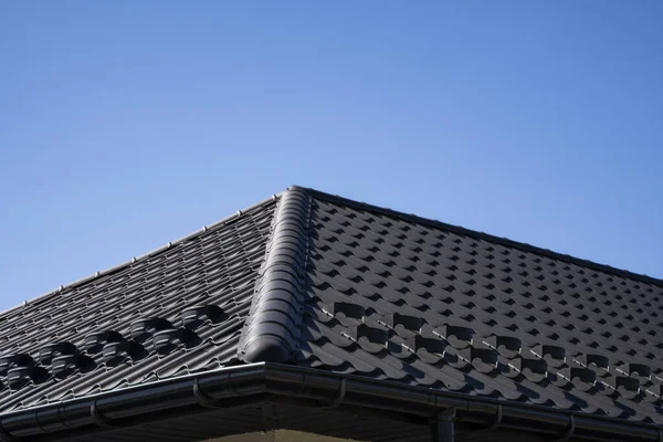 Brown corrugated metal profile roof installed on a modern house. The roof of corrugated sheet. Roofing of metal profile wavy shape. Modern roof made of metal. Metal roofing.