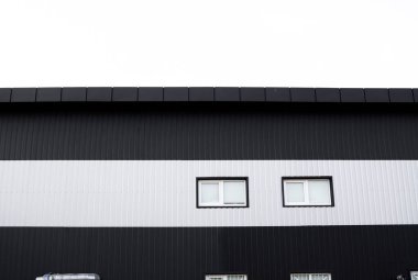 Siyah ve beyaz kıvrımlı demir levha bir depo ya da pencereli fabrika cephesi olarak kullanılıyor. Sivri uçlu çinko kaplamalı metal alüminyum cephenin dokusu. Mimarlık. Metal doku.