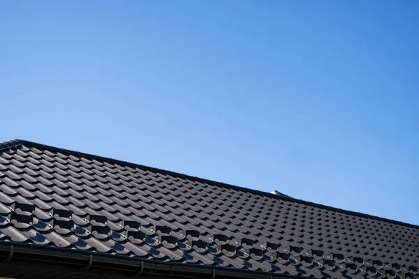 Brown corrugated metal profile roof installed on a modern house. The roof of corrugated sheet. Roofing of metal profile wavy shape. Modern roof made of metal. Metal roofing.