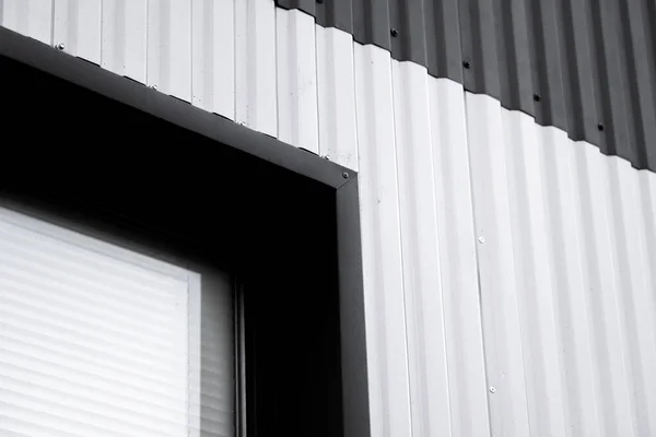 Черно-белый гофрированный железный лист используется как фасад склада или фабрики с окном. Текстура бесшовного гофрированного металлического алюминиевого фасада из цинкового листа. Архитектура. Текстура металла. — стоковое фото