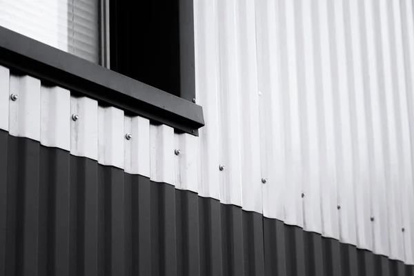 Hoja de hierro corrugado en blanco y negro utilizada como fachada de un almacén o fábrica con ventana. Textura de una fachada de aluminio de chapa de zinc corrugado sin costura. Arquitectura. Textura metálica. — Foto de Stock