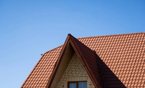 Röd korrugerad metall profil tak installerat på ett modernt hus. Taket på wellpapp. Takläggning av metallprofil vågig form. Modernt tak av metall. Takläggning av metall. — Stockfoto