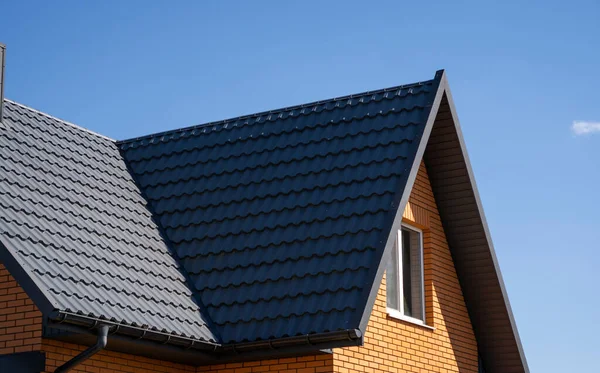 Grijs gegolfd metalen profieldak geïnstalleerd op een modern huis. Het dak van golfplaten. Dakbedekking van metalen profiel golvende vorm. Modern dak van metaal. Metalen dakbedekking. — Stockfoto