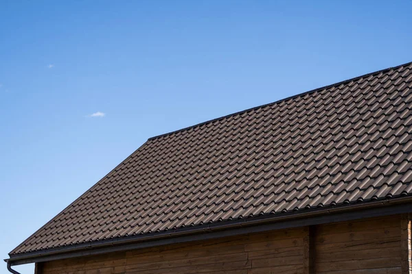 Brown corrugated metal profile roof installed on a modern house. The roof of corrugated sheet. Roofing of metal profile wavy shape. Modern roof made of metal. Metal roofing.