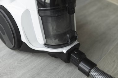 Gri bir fayansta torbasız hortum süpürgesi. Aspirasyon vasıtasıyla zeminden ve diğer yüzeylerden toz ve küçük parçacıkları toplayan elektrikli cihazlar..