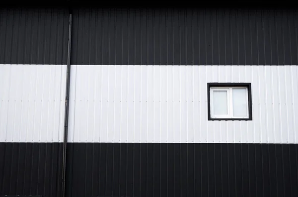 Hoja de hierro corrugado en blanco y negro utilizada como fachada de un almacén o fábrica con ventanas. Textura de una fachada de aluminio de chapa de zinc corrugado sin costura. Arquitectura. Textura metálica. — Foto de Stock