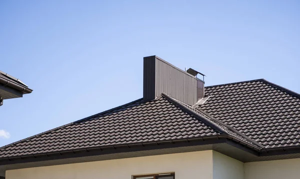 Коричневая гофрированная металлическая крыша, установленная на современном доме. Крыша из гофрированного листа. Крыша металлического профиля волнистой формы. Современная крыша из металла. Металлическая кровля. — стоковое фото