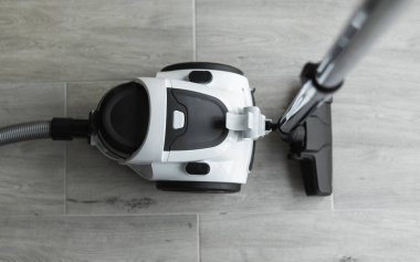 Gri bir fayansta torbasız hortum süpürgesi. Aspirasyon vasıtasıyla zeminden ve diğer yüzeylerden toz ve küçük parçacıkları toplayan elektrikli cihazlar..