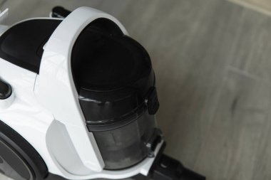 Gri bir fayansta torbasız hortum süpürgesi. Aspirasyon vasıtasıyla zeminden ve diğer yüzeylerden toz ve küçük parçacıkları toplayan elektrikli cihazlar..