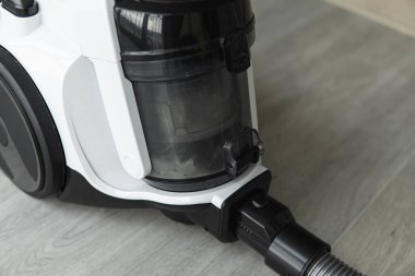 Gri bir fayansta torbasız hortum süpürgesi. Aspirasyon vasıtasıyla zeminden ve diğer yüzeylerden toz ve küçük parçacıkları toplayan elektrikli cihazlar..
