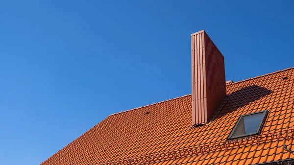 Red corrugated metal profile roof installed on a modern house. The roof of corrugated sheet. Roofing of metal profile wavy shape. Modern roof made of metal. Metal roofing.