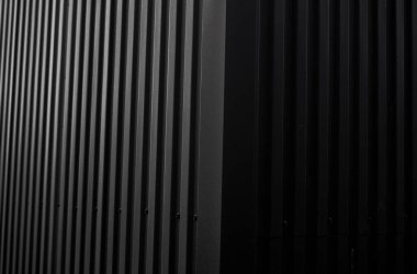 Bir depo ya da fabrika cephesi olarak kullanılan siyah kıvrımlı demir çarşaf. Sivri uçlu çinko kaplamalı metal alüminyum cephenin dokusu. Mimarlık. Metal doku.