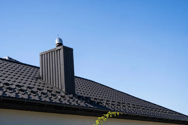 Brown corrugated metal profile roof installed on a modern house. The roof of corrugated sheet. Roofing of metal profile wavy shape. Modern roof made of metal. Metal roofing.