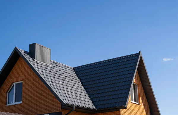 Grey corrugated metal profile roof installed on a modern house. The roof of corrugated sheet. Roofing of metal profile wavy shape. Modern roof made of metal. Metal roofing.