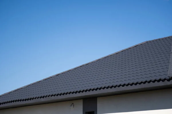 Brown corrugated metal profile roof installed on a modern house. The roof of corrugated sheet. Roofing of metal profile wavy shape. Modern roof made of metal. Metal roofing. — Stock Photo, Image