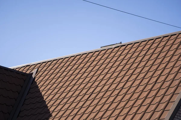 Brown corrugated metal profile roof installed on a modern house. The roof of corrugated sheet. Roofing of metal profile wavy shape. Modern roof made of metal. Metal roofing.