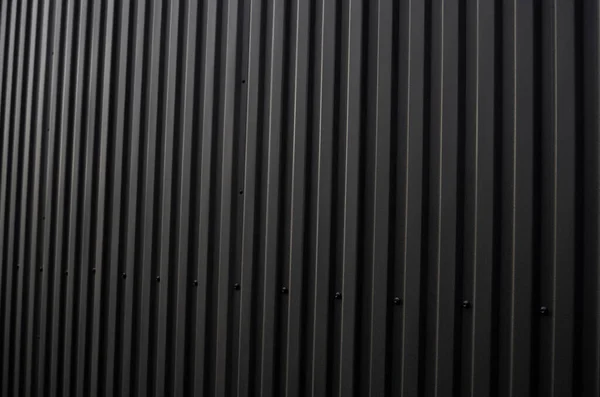 Hoja de hierro ondulado negro utilizada como fachada de un almacén o fábrica. Textura de una fachada de aluminio de chapa de zinc corrugado sin costura. Arquitectura. Textura metálica. — Foto de Stock