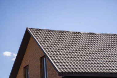 Modern bir eve kahverengi, metal profil çatısı döşenmiş. Çürük çarşafın çatısı. Metal profil dalgalı şeklinin çatısı. Metalden yapılmış modern çatı. Metal çatı..