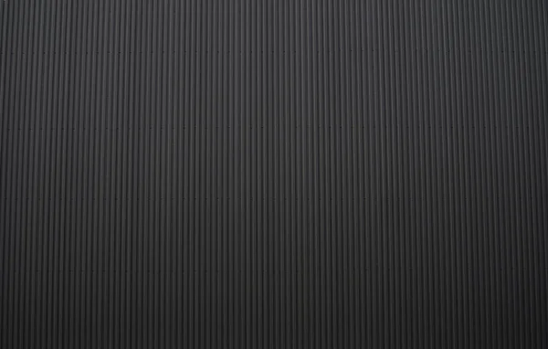 Feuille de fer ondulé noir utilisé comme façade d'un entrepôt ou d'une usine. Texture d'une façade en aluminium ondulé sans soudure en tôle de zinc. L'architecture. Texture métallique. — Photo