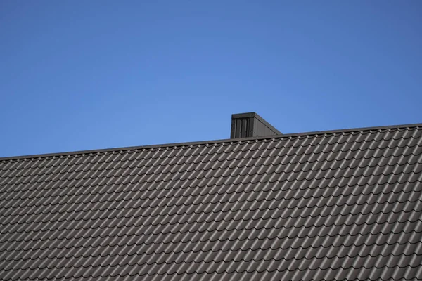 갈색 주름진 금속 프로파일 지붕 이 현대 주택에 설치되어 있다. 골함석의 지붕. 금속 프로파일의 뿌리 모양이 뒤엉켜 있다. 현대의 지붕은 금속으로 만들어 졌다. 금속 지붕. — 스톡 사진