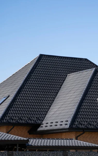 Brown corrugated metal profile roof installed on a modern house. The roof of corrugated sheet. Roofing of metal profile wavy shape. Modern roof made of metal. Metal roofing.