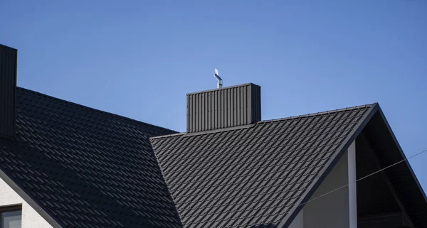 Grey corrugated metal profile roof installed on a modern house. The roof of corrugated sheet. Roofing of metal profile wavy shape. Modern roof made of metal. Metal roofing.