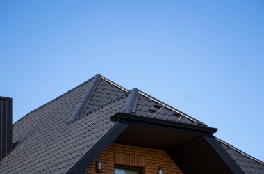 Modern bir eve kahverengi, metal profil çatısı döşenmiş. Çürük çarşafın çatısı. Metal profil dalgalı şeklinin çatısı. Metalden yapılmış modern çatı. Metal çatı..