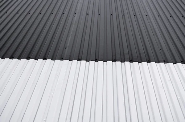 Schwarz-weißes Wellblech, das als Fassade einer Lagerhalle oder Fabrik verwendet wird. Textur einer nahtlosen Wellblechfassade aus Aluminium. Architektur. Metallstruktur. — Stockfoto