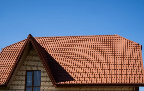 Modern bir evin çatısına kırmızı kıvrımlı metal profil çatısı döşenmiş. Çürük çarşafın çatısı. Metal profil dalgalı şeklinin çatısı. Metalden yapılmış modern çatı. Metal çatı.. — Stok fotoğraf
