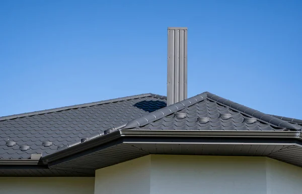 Grey corrugated metal profile roof installed on a modern house. The roof of corrugated sheet. Roofing of metal profile wavy shape. Modern roof made of metal. Metal roofing.