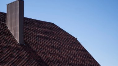 Modern bir eve kahverengi, metal profil çatısı döşenmiş. Çürük çarşafın çatısı. Metal profil dalgalı şeklinin çatısı. Metalden yapılmış modern çatı. Metal çatı..