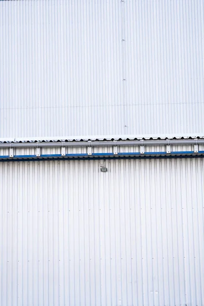 White corrugated iron sheet used as a facade of a warehouse or factory. Texture of a seamless corrugated zinc sheet metal aluminum facade. Architecture. Metal texture.