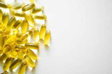 Beyaz arka planda parlak sarı omega-3 kapsülleri, sağlıklı yaşam tarzını, destek bakımını ve modern sağlık kavramını temsil ediyor..