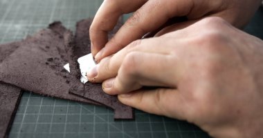 Montajdan önce deri parçalarına yapıştırıcı süren el sanatları ve el işçiliğini gösteren el sanatları işçilerinin yakın plan görüntüleri..