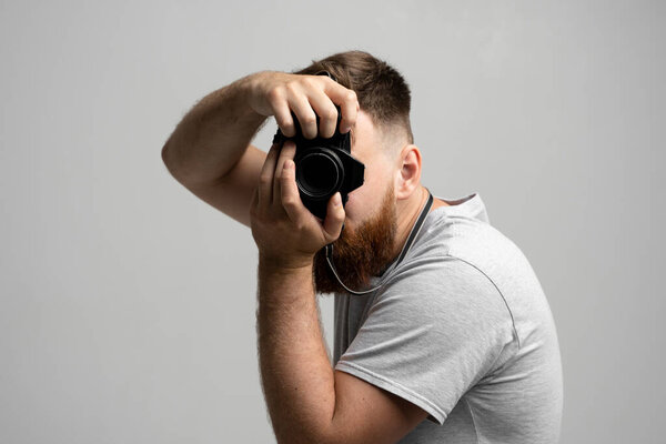 Professional male photographer holding camera and taking picture in studio, concept of creativity, media, and visual content production.